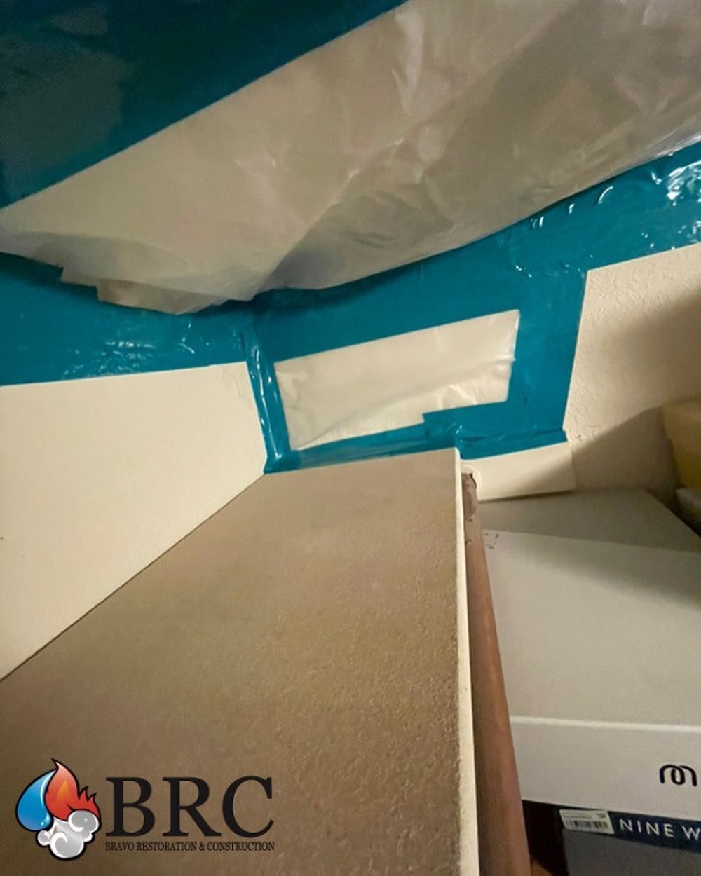 An indoor scene showing a water-damaged ceiling covered with duct tape, with a close view of stored cardboard boxes.