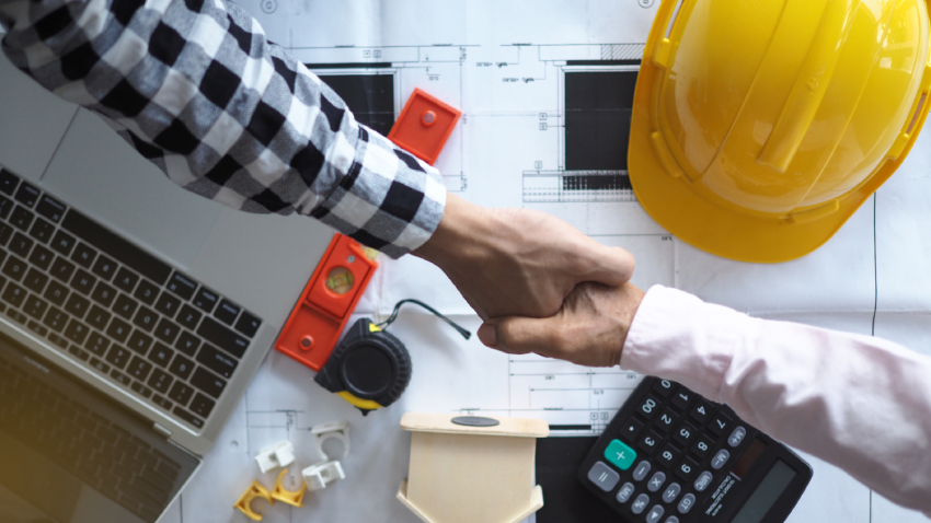 A restoration expert and general contract shake hands over their plans.